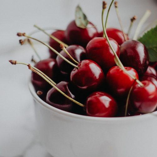 red cherries in white ceramic bowl